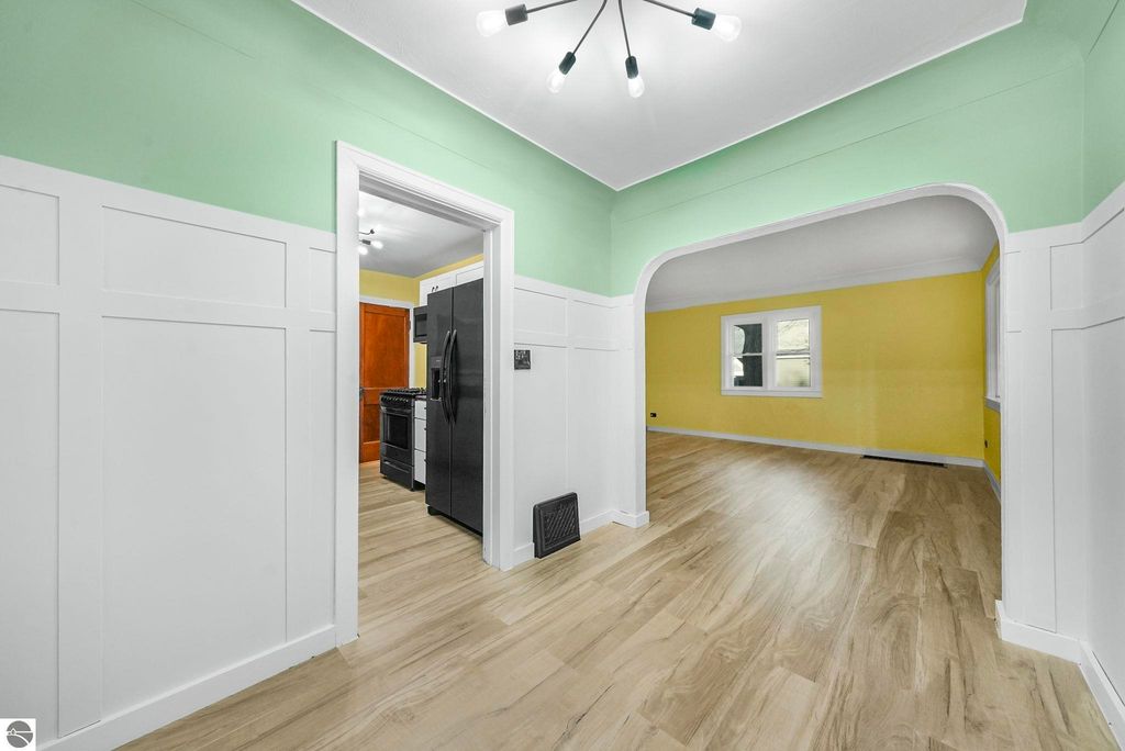 Updated interior of home at 310 E Euclid Street, featuring green and yellow walls, modern light fixture, and open layout with hardwood flooring.
