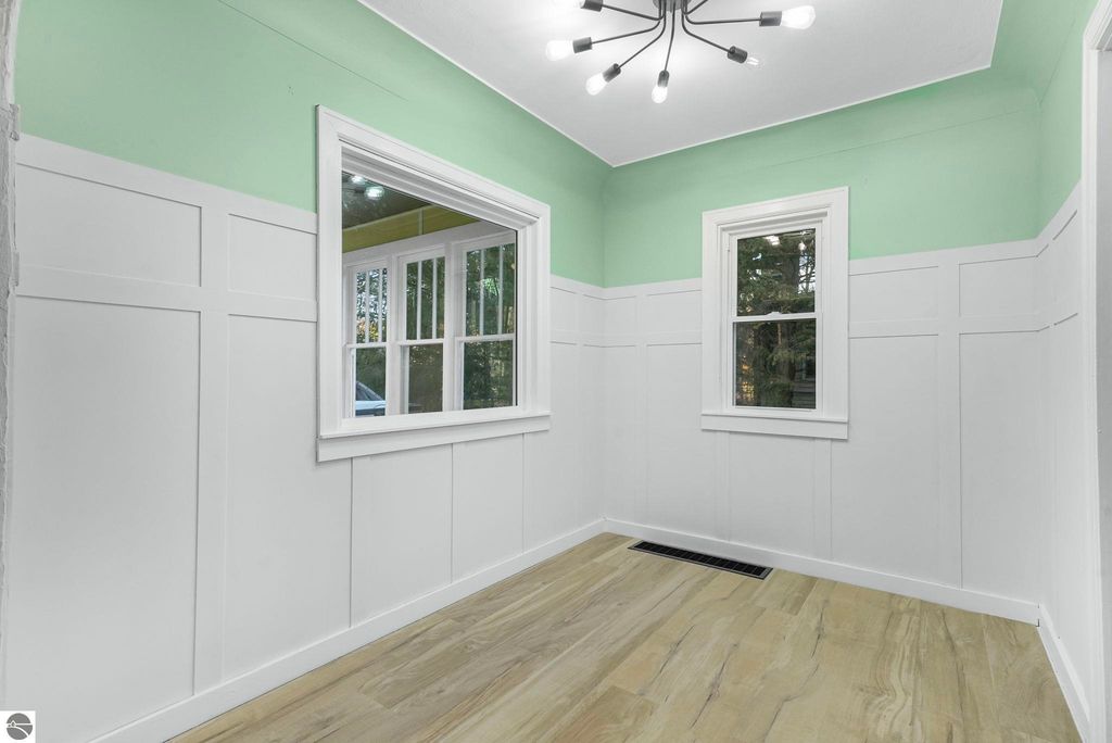 Updated entryway with green accent wall, large windows, and modern lighting in McBain, MI home listing at 310 E Euclid Street.
