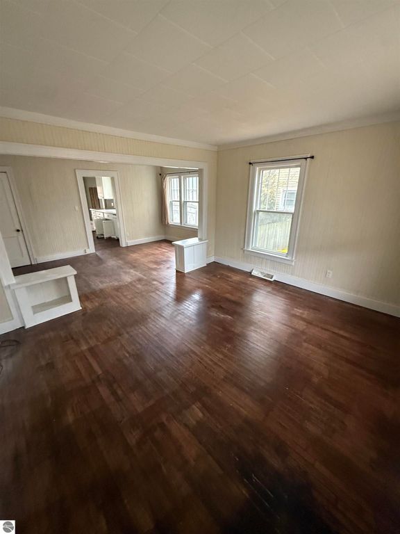 Spacious living area of 610 S Washington Street, featuring hardwood floors, large windows for natural light, and a view into the kitchen, ideal for comfortable family living.