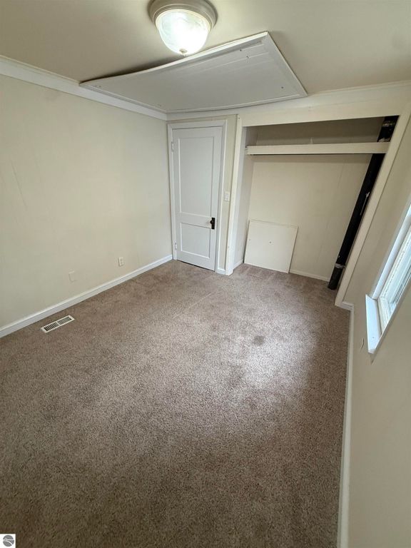 Cozy bedroom with beige carpeting, closet space, and natural light from window, part of the real estate listing for 610 S Washington Street, Mt Pleasant, MI.