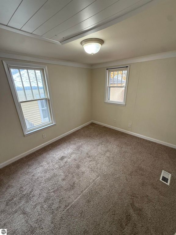 Cozy interior room with beige walls, carpeted floor, and two windows allowing natural light, showcasing the inviting layout of the home at 610 S Washington Street, Mt Pleasant, MI.