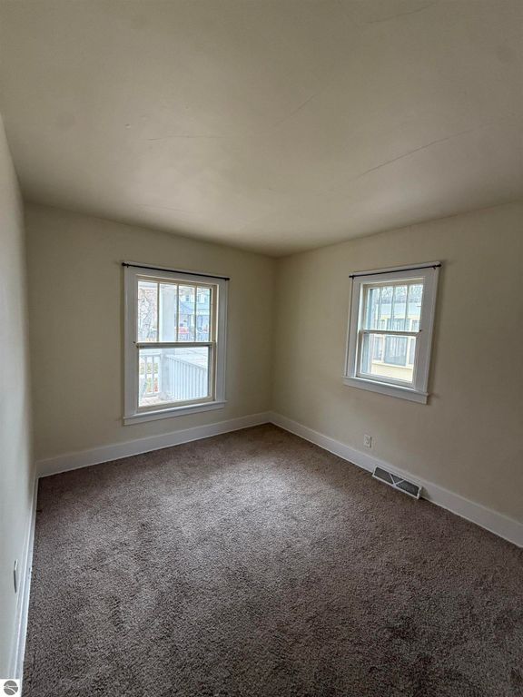Cozy bedroom with natural light from two windows, featuring beige walls and plush carpet, suitable for a home at 610 S Washington Street, Mt Pleasant, MI.