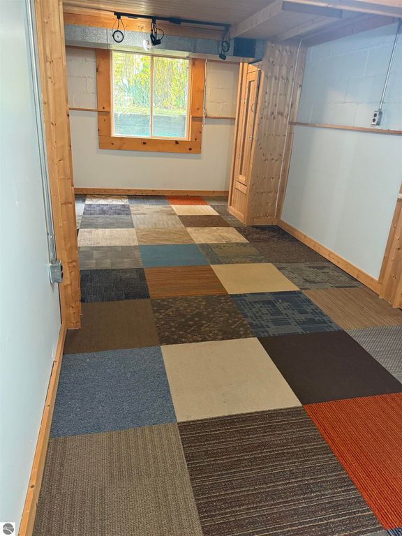 Interior hallway featuring a multi-colored carpet with square patterns, wooden accents, and a window allowing natural light, suitable for a residential property listing at 610 S Washington Street, Mt Pleasant, MI.