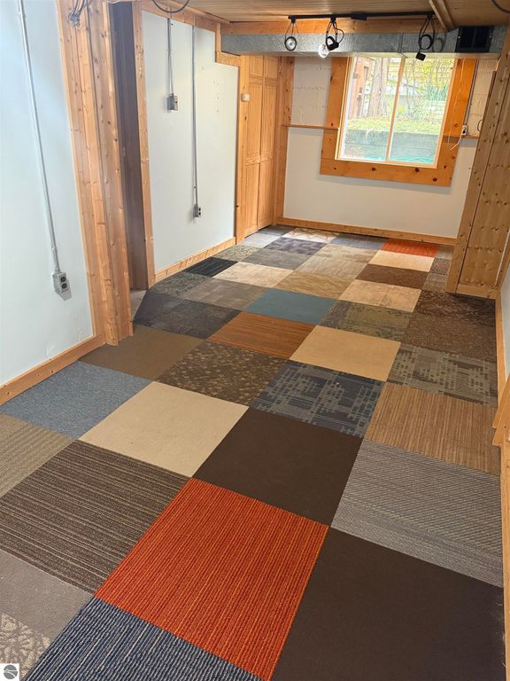 Interior view of a room at 610 S Washington Street, featuring a multi-colored carpet tile floor, wooden walls, and a window allowing natural light, highlighting the home's inviting atmosphere in a quiet neighborhood.