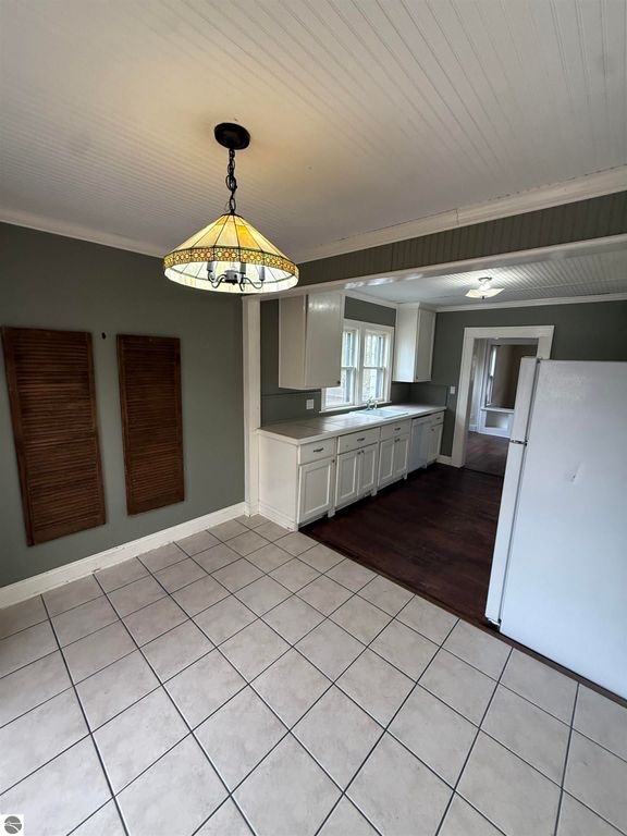 Kitchen interior of 610 S Washington St, featuring white cabinetry, tiled flooring, and a decorative light fixture, showcasing a warm and inviting atmosphere in a residential setting.