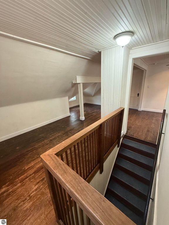 Spacious upper landing with hardwood floors, wooden railing, and access to rooms in a residential property at 610 S Washington Street, Mt Pleasant, MI.