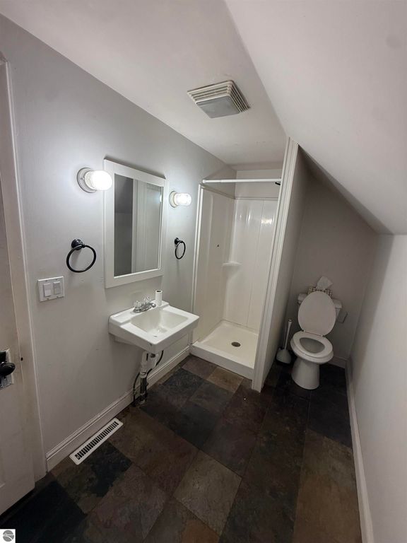 Bathroom with shower, sink, and toilet featuring modern fixtures and slate flooring in residential property at 610 S Washington Street, Mt Pleasant, MI.