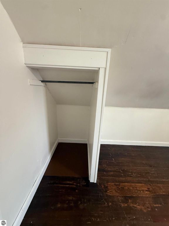 Closet space with white walls and dark wood flooring, showcasing a simple design suitable for the home at 610 S Washington Street, Mt Pleasant, MI.