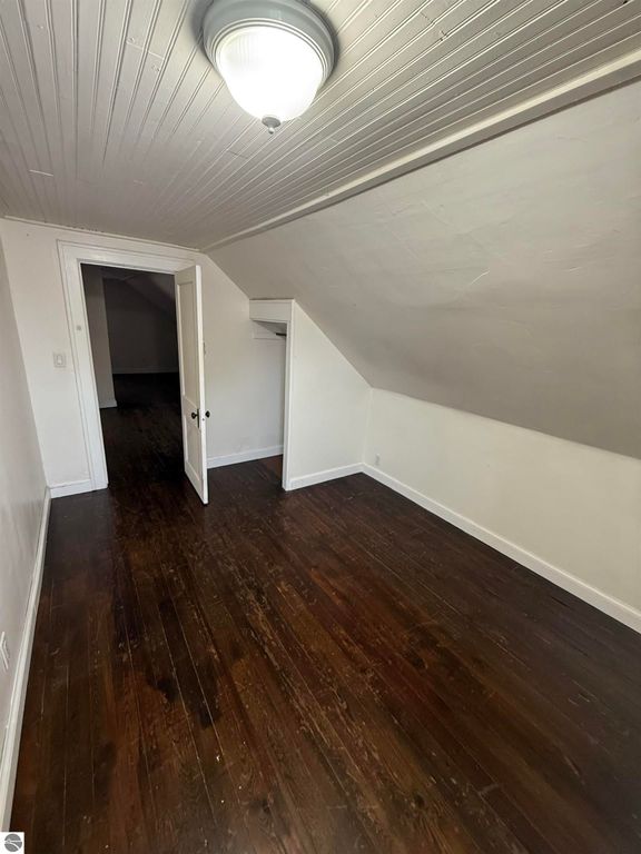 Spacious interior view of a room in a home at 610 S Washington Street, featuring wooden flooring, sloped ceiling, and closet space, showcasing the inviting layout ideal for comfortable living in Mount Pleasant, MI.