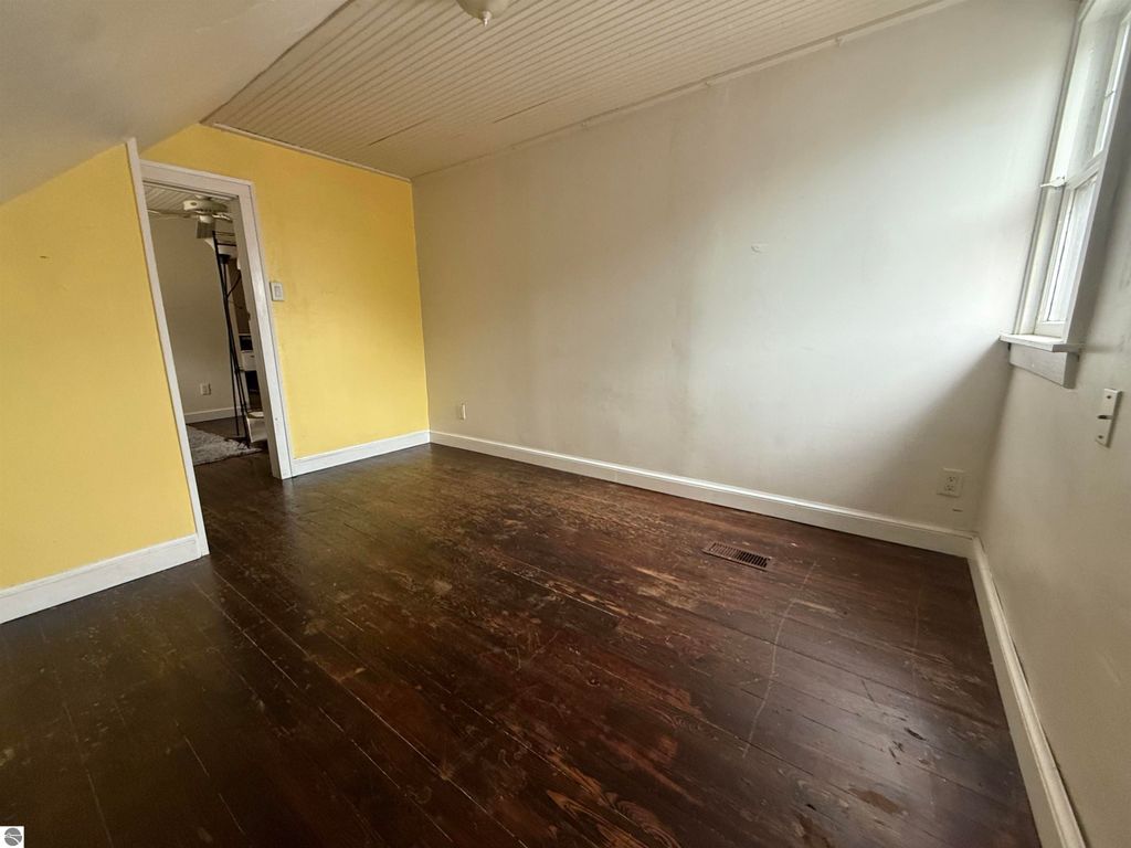 Interior view of a room at 610 S Washington Street, featuring yellow walls, hardwood flooring, and a window providing natural light, suitable for potential buyers exploring the property.