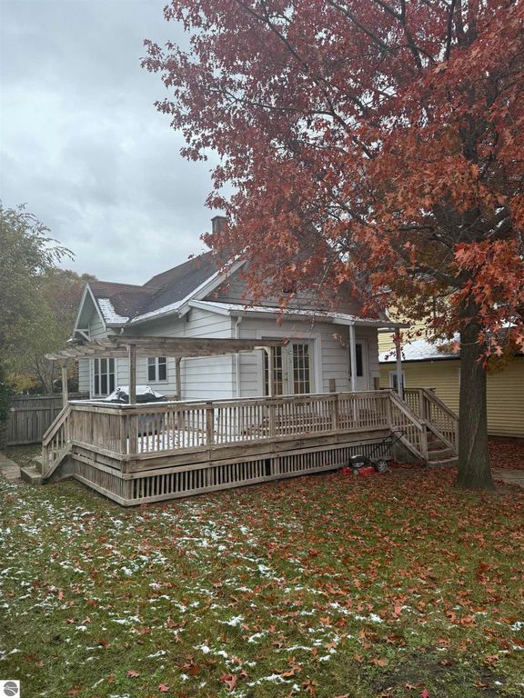 Charming residential home at 610 S Washington St, featuring a spacious wooden deck, surrounded by vibrant autumn foliage and a well-maintained yard, ideal for outdoor activities.