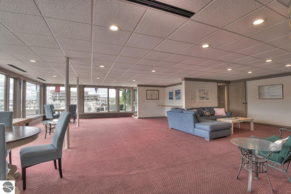 Interior view of a lounge area in a private yacht club, featuring comfortable seating, tables, and large windows overlooking a marina, reflecting amenities available for boat enthusiasts near Traverse City.