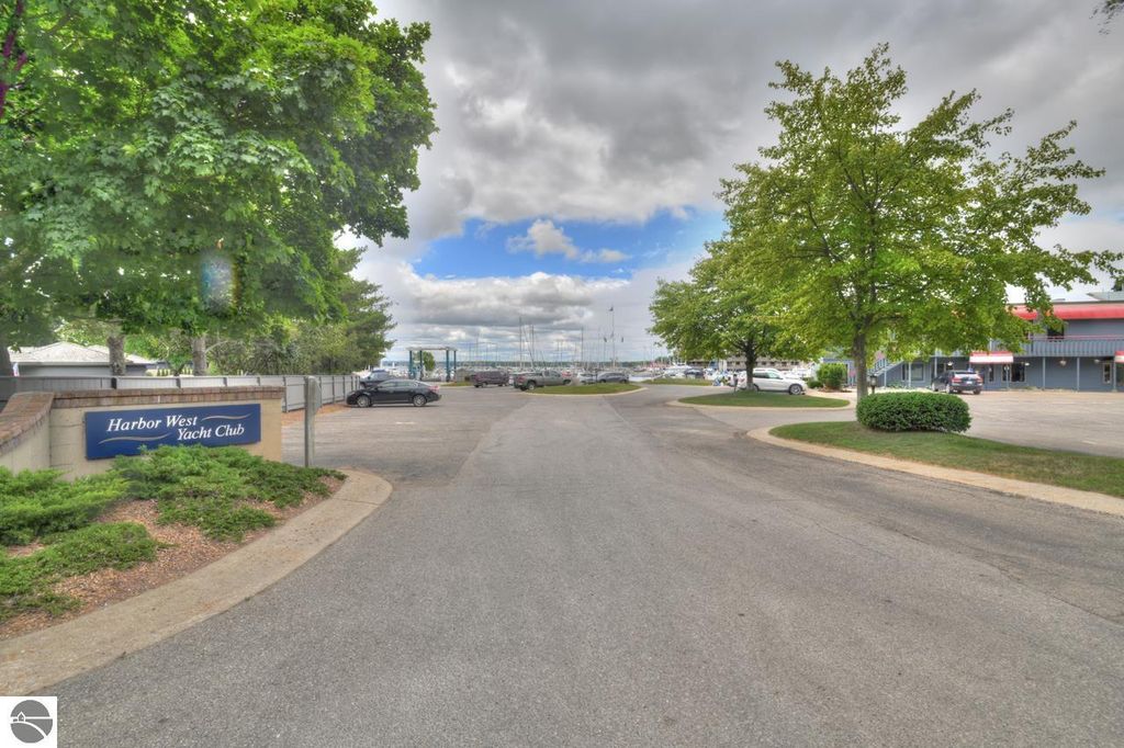 Harbor West Yacht Club sign at entrance with trees and marina in background, located in Traverse City, Michigan, near West Bay.