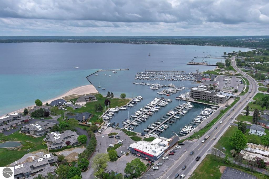 Aerial view of Traverse City marina with numerous boat slips, West Bay shoreline, and nearby residential areas, highlighting the waterfront amenities and access to water activities.