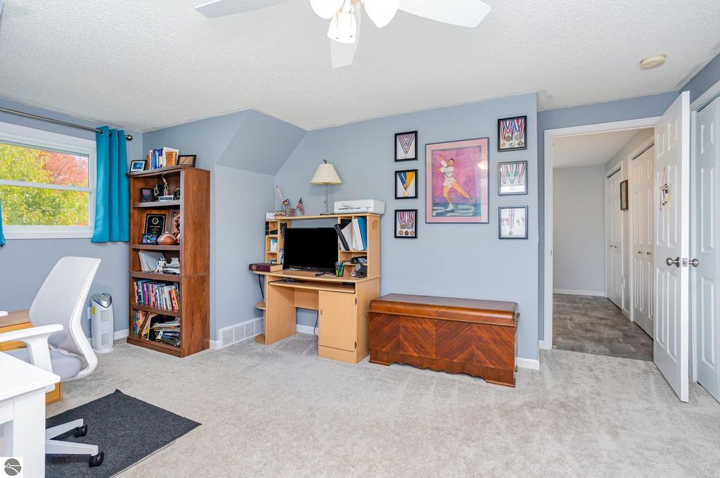 Updated home office with desk and chair, bookshelf, decorative wall art, and natural light from window, showcasing a cozy and inviting workspace.