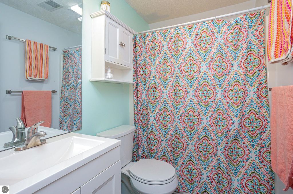 Brightly decorated bathroom featuring a colorful patterned shower curtain, modern sink, and fresh towels, highlighting the home's updated interior at 1932 Churchill Boulevard, Mt Pleasant, MI.