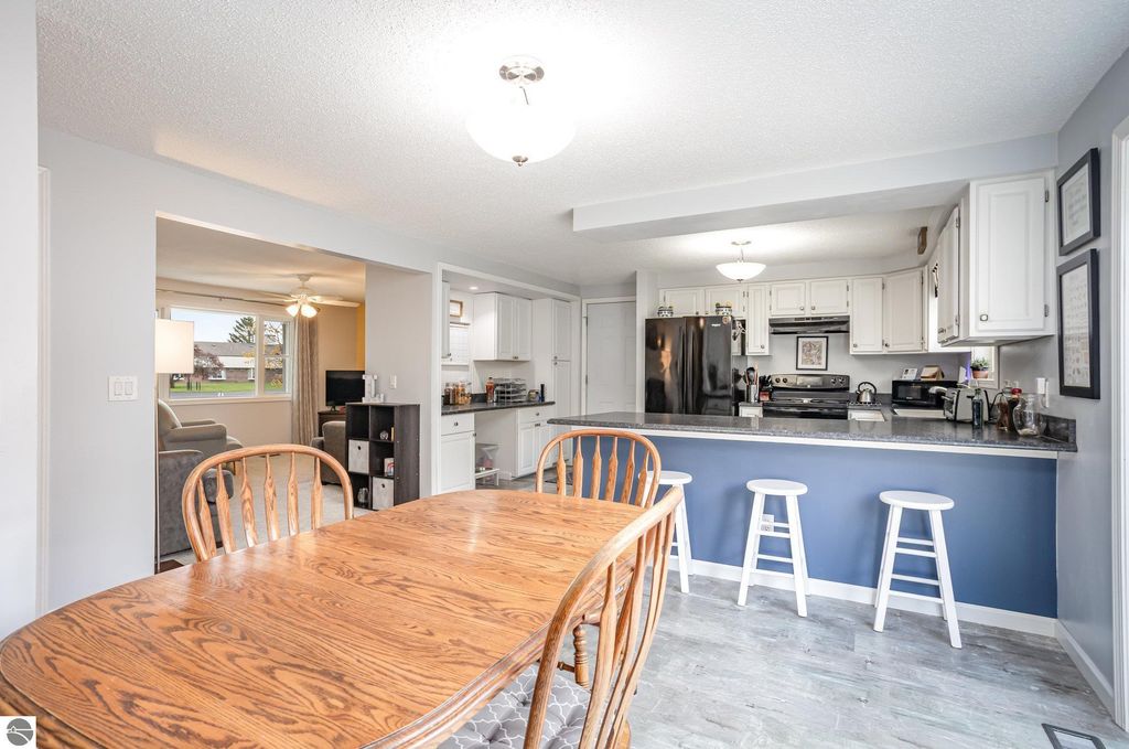 Updated kitchen and dining area in a 3-bedroom home, featuring wooden dining table, white cabinetry, black appliances, and modern decor, showcasing a bright and inviting atmosphere.