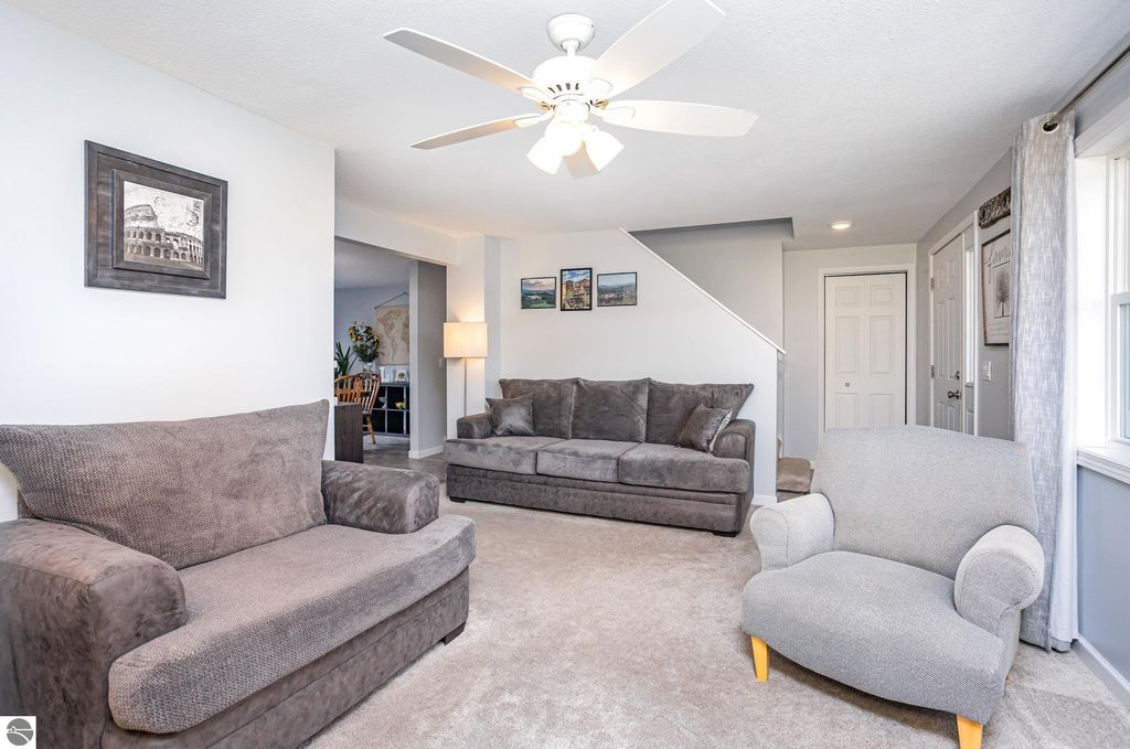 Living room interior of a 3-bedroom home at 1932 Churchill Boulevard, featuring plush gray sofas, a light gray accent chair, and decorative wall art, with natural light streaming through the windows, creating a welcoming atmosphere.