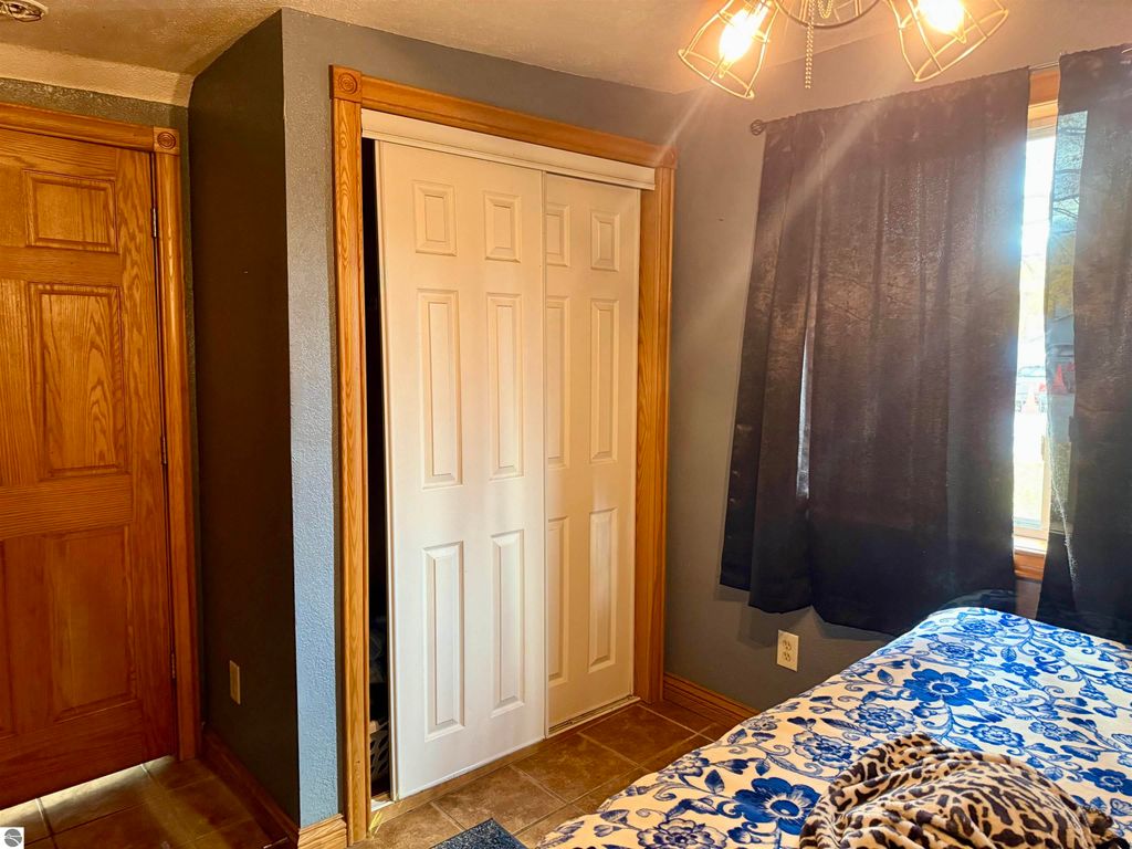 Interior view of a cozy bedroom in Breckenridge home, featuring a blue floral bedspread, closet doors, wooden trim, and black curtains, highlighting the inviting space of the 3-bedroom, 2-bathroom listing at 325 Main Street.