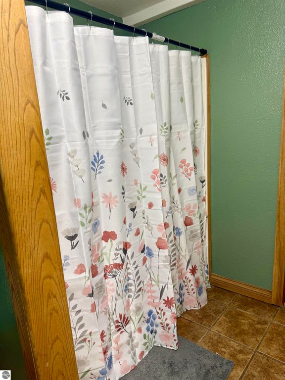 Shower curtain with floral design in a bathroom setting at 325 Main Street, Breckenridge, MI, showcasing home interior features.