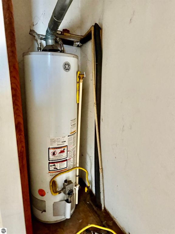 Water heater in a residential setting, featuring a GE brand unit with visible gas line and safety instructions, relevant to home features in the Breckenridge listing.