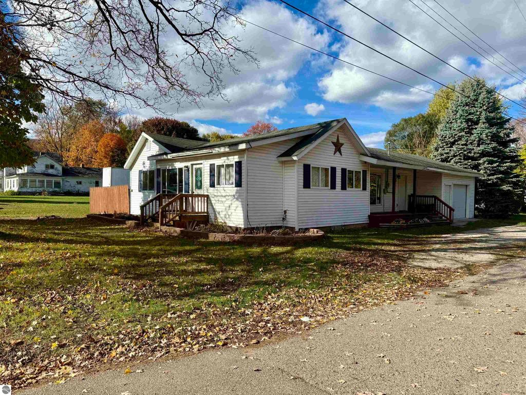 Charming single-family home at 325 Main Street, Breckenridge, MI, featuring a welcoming front porch, star decoration, and surrounded by colorful autumn foliage.