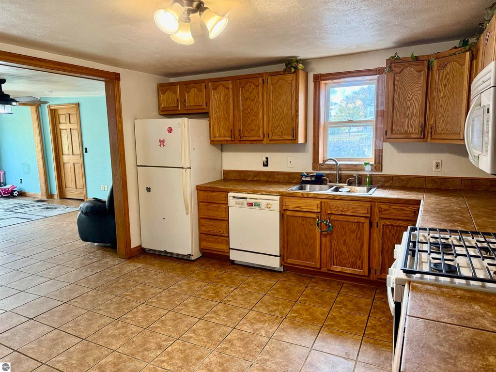 Kitchen interior of a charming home at 325 Main Street, Breckenridge, featuring wooden cabinets, white appliances, and a tiled floor, showcasing an open layout ideal for family living.