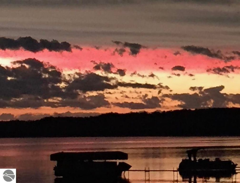Sunset over Lake Missaukee with vibrant pink and orange clouds reflecting on the water, showcasing the tranquil beauty of the area near the cottage for sale at 1779 S Green Road, Lake City, MI.