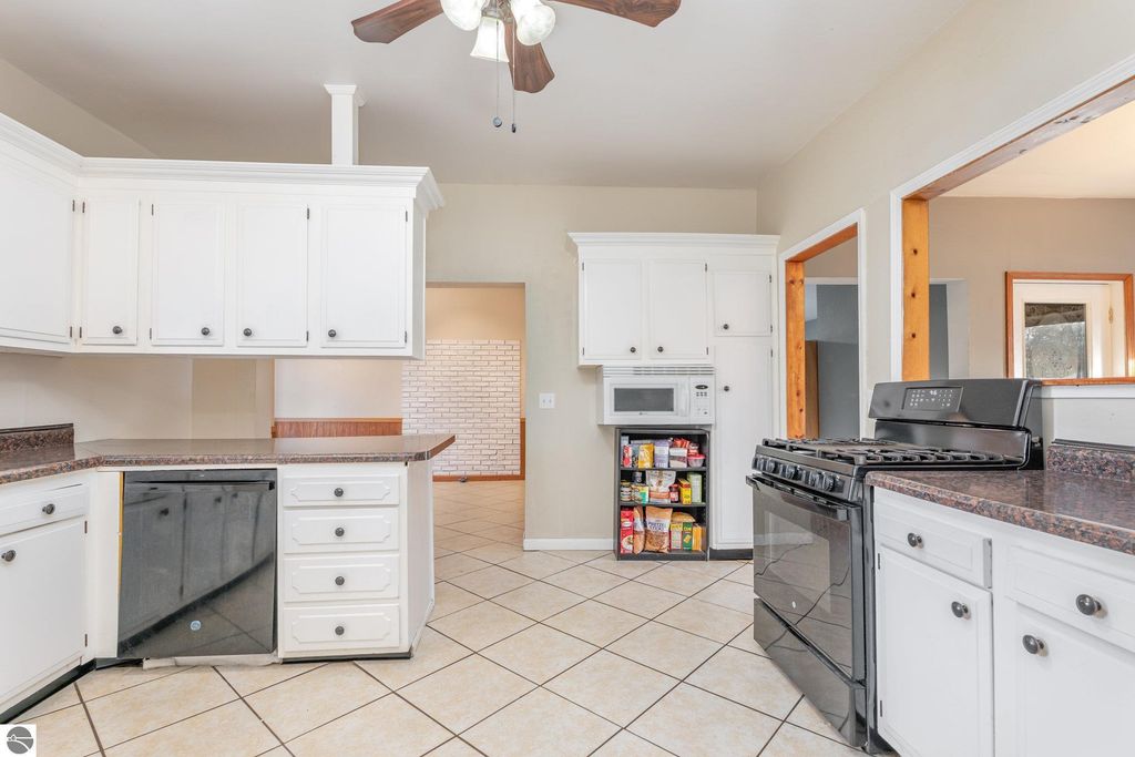 Spacious kitchen in 1708 W Lyons Street, featuring white cabinetry, granite countertops, black gas stove, and tiled flooring, showcasing an open layout ideal for family living and entertaining.