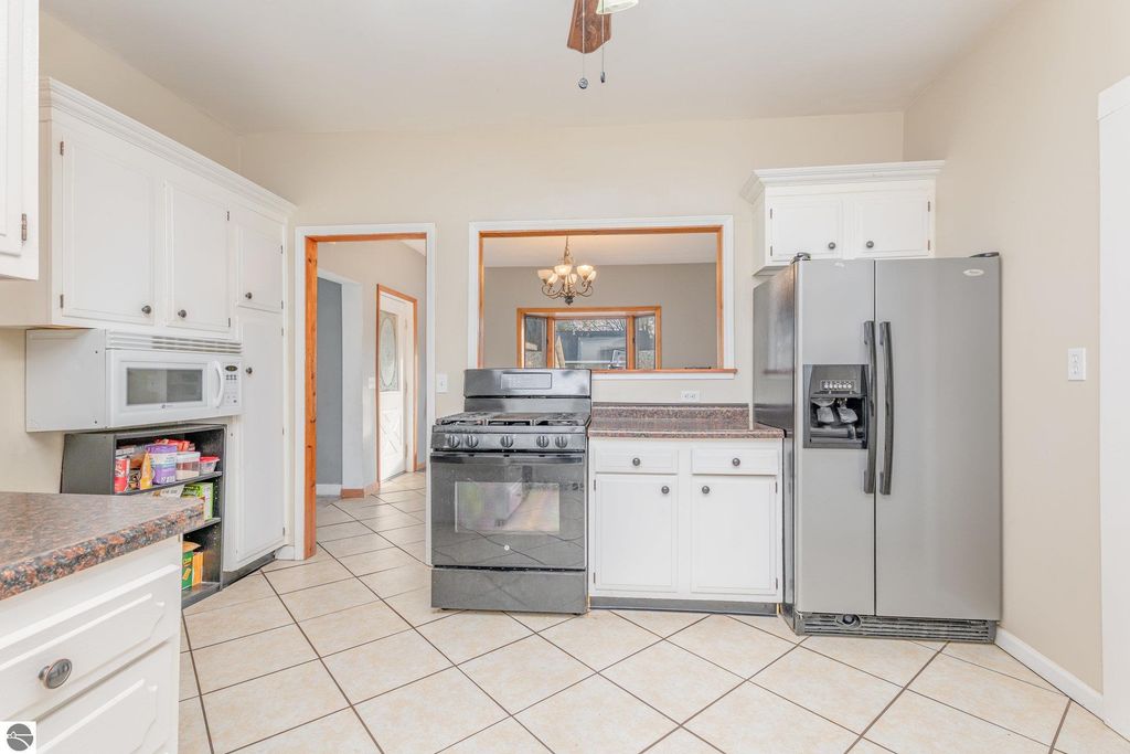 Kitchen interior of 1708 W Lyons Street, featuring white cabinetry, black gas stove, stainless steel refrigerator, and tile flooring, showcasing spacious layout ideal for multi-use living and dining.