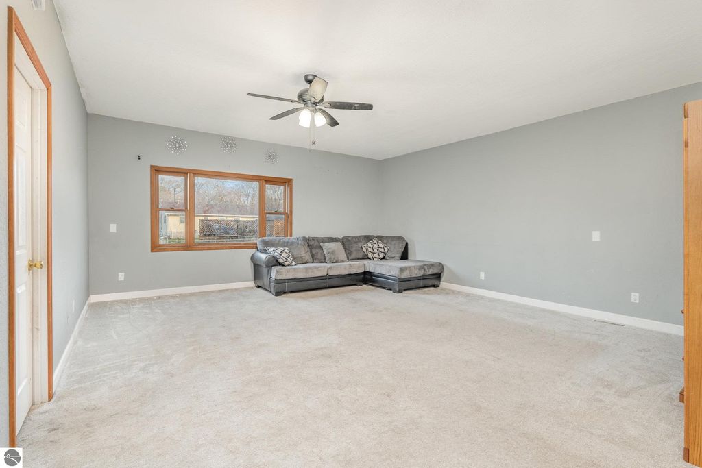 Spacious living room in 1708 W Lyons Street, featuring a gray color scheme, large windows, and a sectional sofa, ideal for versatile living in Mt. Pleasant, MI.