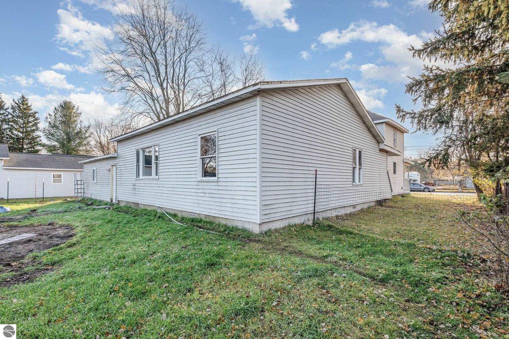 Exterior view of the side yard of 1708 W Lyons Street, showcasing the home's siding, windows, and surrounding greenery in Mt. Pleasant, MI.