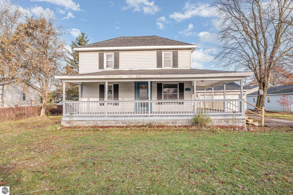 Spacious two-story home at 1708 W Lyons Street, Mt Pleasant, featuring a wrap-around porch, large yard, and surrounded by trees.
