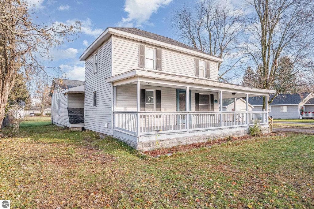 Spacious two-story home at 1708 W Lyons Street, Mt Pleasant, featuring a wrap-around covered porch, large yard, and adjacent two-car garage.