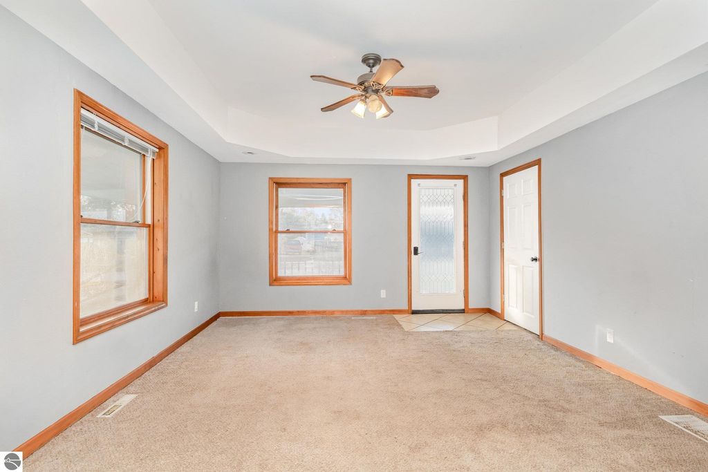 Spacious living area in 1708 W Lyons Street, featuring large windows, carpeted flooring, and a ceiling fan, showcasing versatile multi-use space for living and dining.