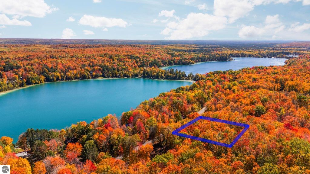 Aerial view of vibrant autumn foliage surrounding two lakes, highlighting a marked parcel of land in the Blue Lake Heights community, near 7149 W Blue Lake Road, Kalkaska, MI.