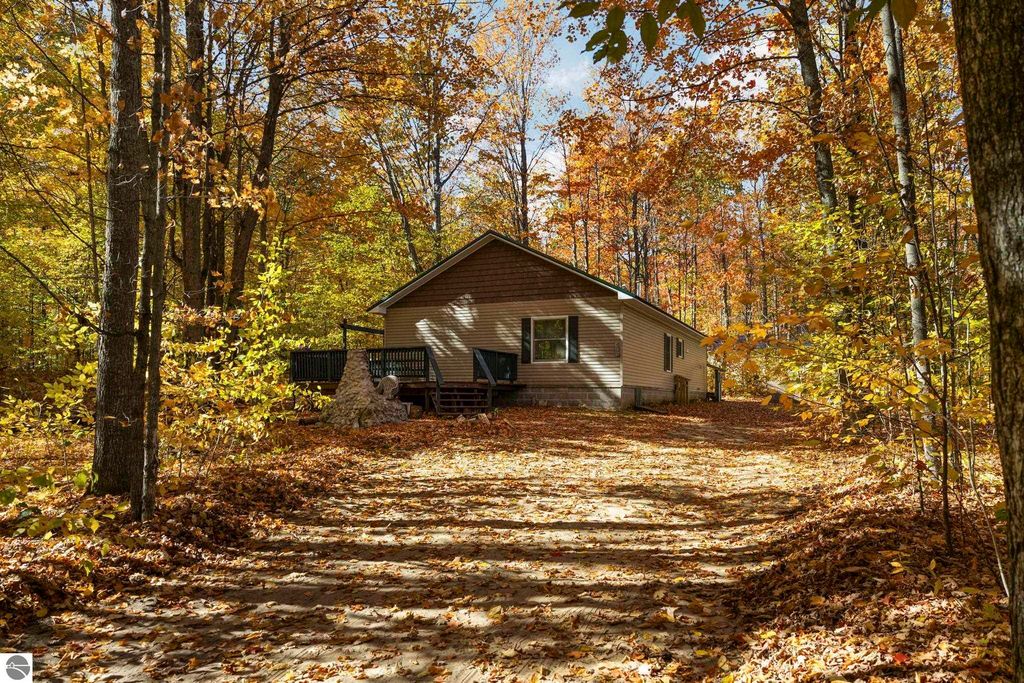 3-bedroom home on corner lot surrounded by autumn foliage in Blue Lake Heights, Kalkaska, MI, featuring a custom stone fireplace and natural gas service.