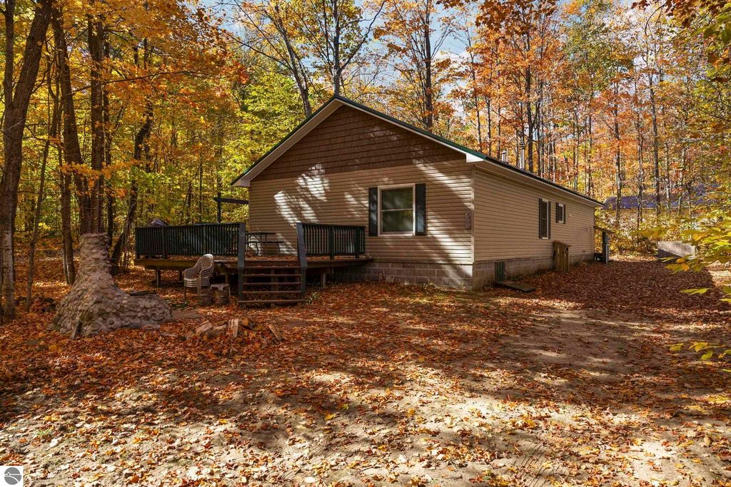 3-bedroom, 2-bath home on corner lot in Blue Lake Heights, surrounded by autumn foliage, featuring a deck and stone fireplace, ideal for outdoor living and recreation.