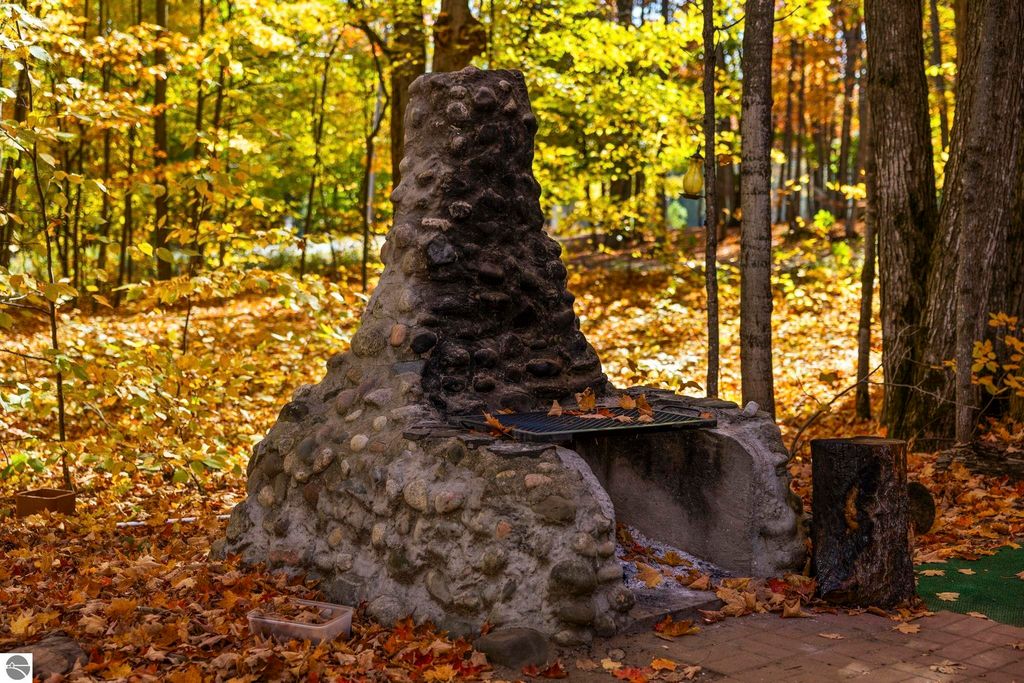 Custom-built stone fireplace surrounded by autumn foliage in a serene outdoor setting near Blue Lake, ideal for gatherings and relaxation.