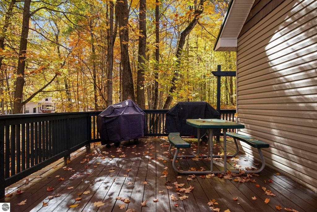 Deck area with picnic table surrounded by vibrant autumn foliage, showcasing a serene outdoor space ideal for relaxation in the Blue Lake Heights community, near 7149 W Blue Lake Road, Kalkaska, MI.