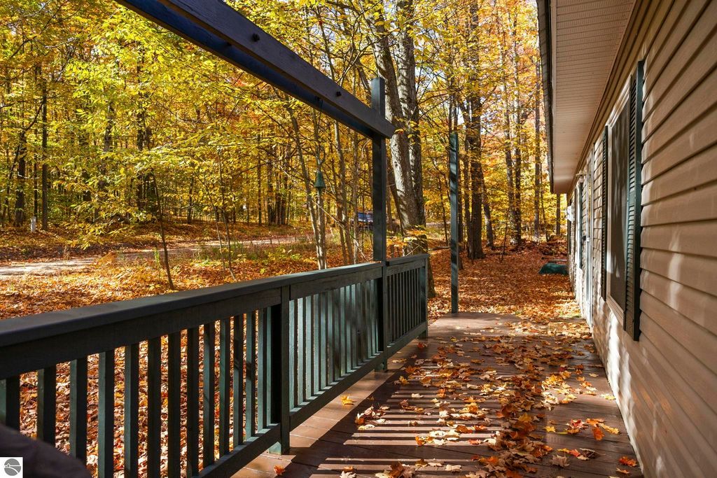 Autumn view from the porch of a 3-bedroom home on W Blue Lake Road, showcasing vibrant fall foliage and a serene wooded area in Kalkaska, MI.