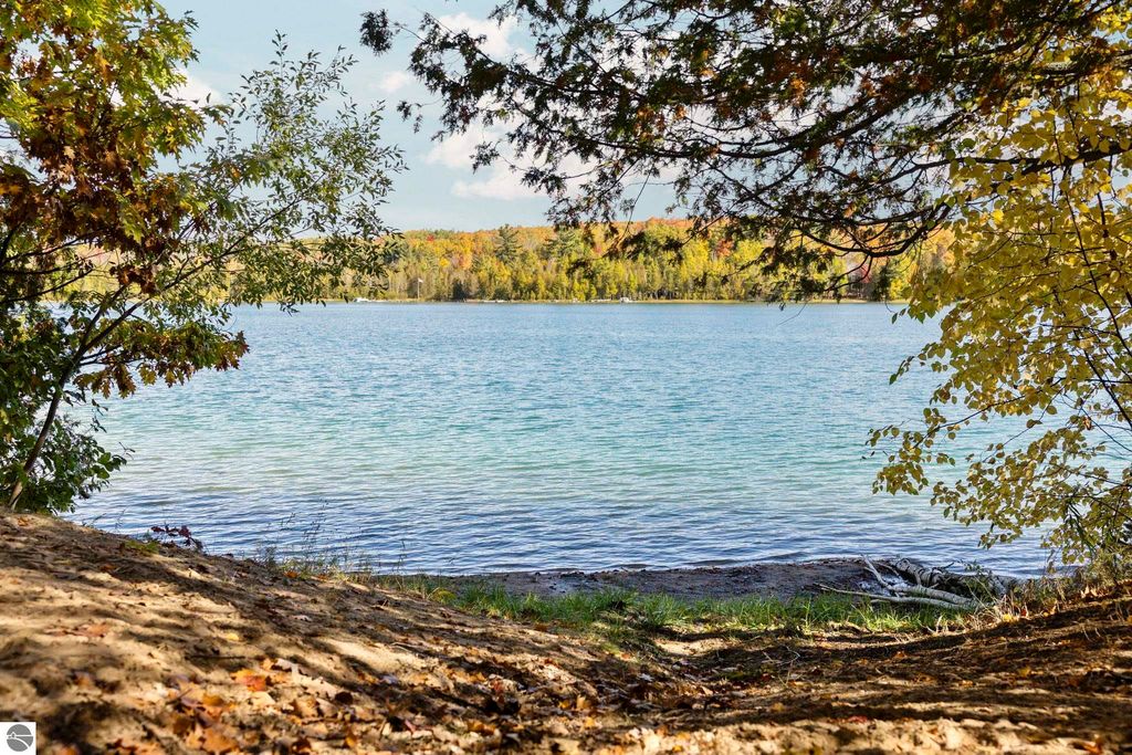 Scenic view of North Blue Lake framed by trees, showcasing calm waters and autumn foliage, highlighting the natural beauty of the Blue Lake Heights community in Kalkaska, MI.
