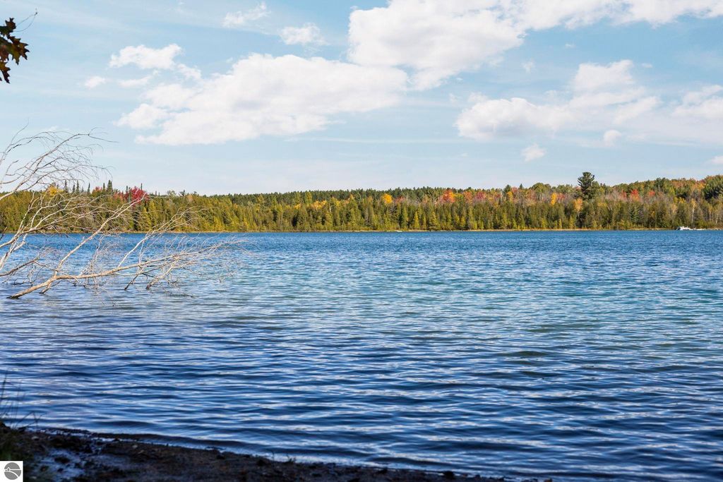 Scenic view of North Blue Lake with calm waters, surrounded by colorful autumn foliage and trees, highlighting the natural beauty of the Blue Lake Heights community in Kalkaska, MI.
