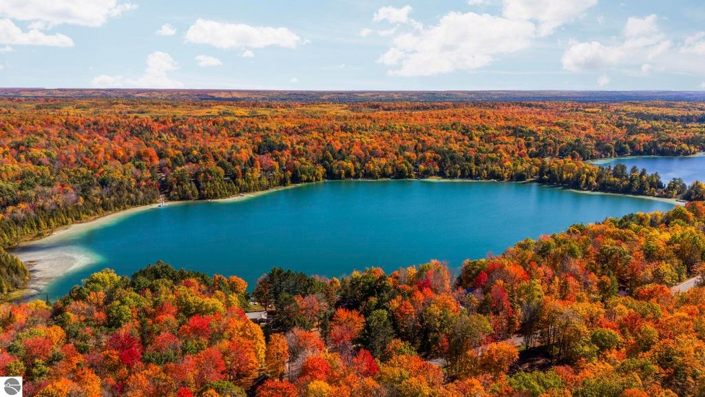 Aerial view of North Blue Lake surrounded by vibrant autumn foliage in Kalkaska, Michigan, showcasing the natural beauty and recreational opportunities in the Blue Lake Heights community.