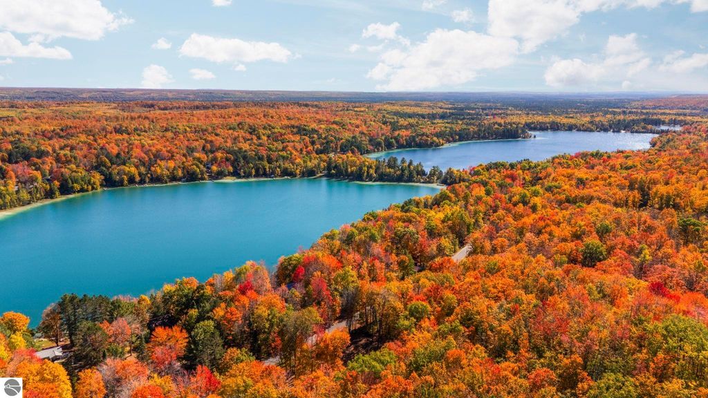 Aerial view of vibrant autumn foliage surrounding two serene lakes in Kalkaska, Michigan, highlighting natural beauty and recreational opportunities near Blue Lake Heights community.