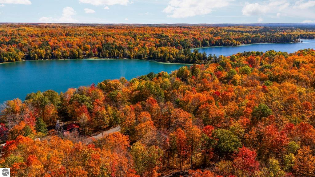 Aerial view of vibrant autumn foliage surrounding North Blue Lake in Kalkaska, MI, showcasing the natural beauty and serene landscape ideal for outdoor activities.