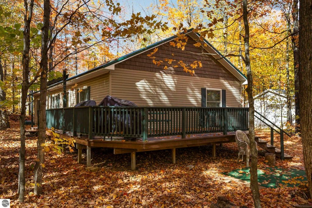 3-bedroom, 2-bath home with a spacious deck surrounded by autumn foliage in Blue Lake Heights, Kalkaska, MI, showcasing Up North living and outdoor charm.