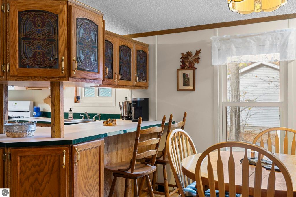 Inviting kitchen with wooden cabinets, green countertops, and dining area featuring a round table and chairs, showcasing a cozy Up North living space at the property on 7149 W Blue Lake Road, Kalkaska, MI.