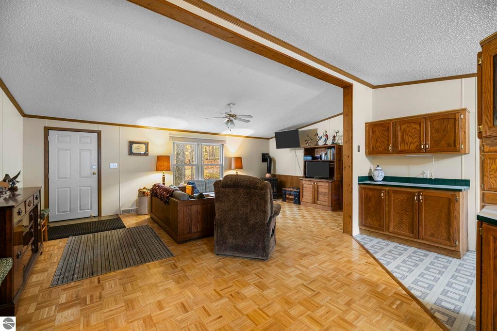 Cozy living room interior of a 3-bedroom home in Kalkaska, featuring wooden cabinetry, a comfortable seating area, and large windows with natural light, showcasing the inviting Up North living atmosphere.