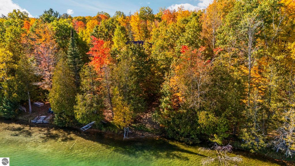 Autumn landscape showcasing vibrant fall foliage along the shoreline of North Blue Lake, with clear water and a serene natural setting near 7149 W Blue Lake Road, Kalkaska, MI.
